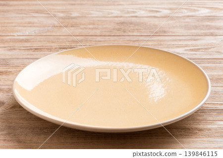Perspective view of empty orange plate on wooden background. Empty space for your design Perspective view of empty orange plate on wooden background. Empty space for your design 139846115