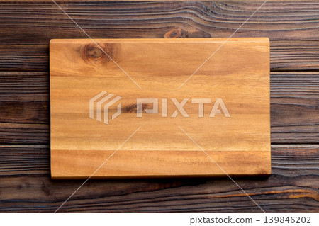 Top view of wooden cutting board on wooden background. Empty space for your design.= Top view of wooden cutting board on wooden background. Empty space for your design.= 139846202