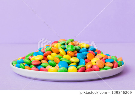 Multicolored candies in a bowl on a colored background. birthday and holiday concept. Top view with copy space Multicolored candies in a bowl on a colored background. birthday and holiday concept. Top view with copy space 139846209