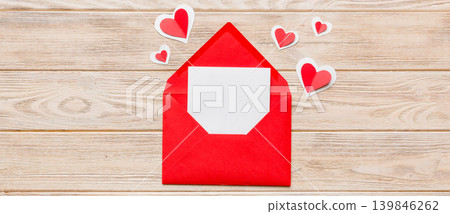 Red paper envelope with empty white card and heart on colored background. top view valentines day concept Red paper envelope with empty white card and heart on colored background. top view valentines day concept 139846262