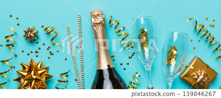 Bottle of champagne with colored glitter, confetti and gift box space for text on colorfull background, top view. Hilarious, christmas and birthday celebration 139846267