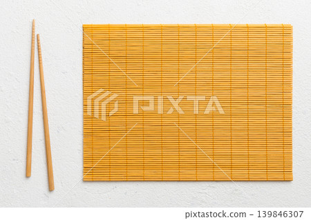 Two chopsticks and bamboo mat on cement background. Top view, copy space Two chopsticks and bamboo mat on cement background. Top view, copy space 139846307