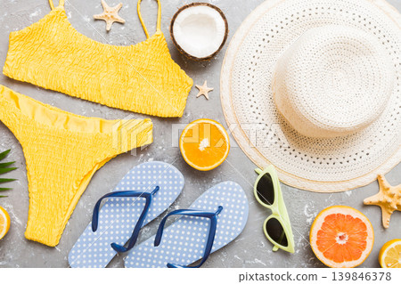 Swimming pool accessories concept. Top view of beach items on table, bright bikini, straw hat, and sunscreen skincare cream. Colorful beach wear. top view Flat lay, copy space Swimming pool accessories concept. Top view of beach items on table, bright bikini, straw hat, and sunscreen skincare cream. Colorful beach wear. top view Flat lay, copy space 139846378