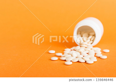 Medicine bottle and white pills spilled on a light background. Medicines and prescription pills flat lay background. White medical pills and tablets spilling out of a drug bottle Medicine bottle and white pills spilled on a light background. Medicines and prescription pills flat lay background. White medical pills and tablets spilling out of a drug bottle 139846446