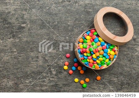 Set of different sweet candy in a paper box with a satin ribbon on a colored background. Holiday concept Set of different sweet candy in a paper box with a satin ribbon on a colored background. Holiday concept 139846459