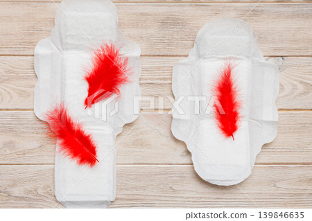 Women hygiene products or Sanitary pad with red feather on colored background. Pastel color. Closeup. Empty place for text. Female daily hygiene Women hygiene products or Sanitary pad with red feather on colored background. Pastel color. Closeup. Empty place for text. Female daily hygiene 139846635