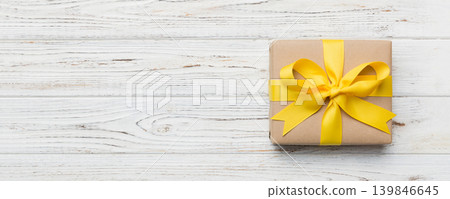 Holiday gift box wrapped in craft paper with colored bow on table background. Top view, flat lay, copy space Holiday gift box wrapped in craft paper with colored bow on table background. Top view, flat lay, copy space 139846645