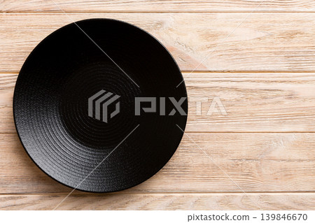 Top view of black plate on wooden background. Empty space for your design Top view of black plate on wooden background. Empty space for your design 139846670