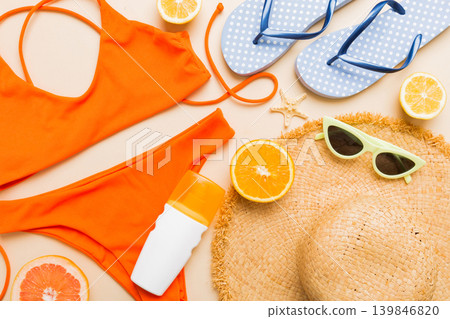 Swimming pool accessories concept. Top view of beach items on table, bright bikini, straw hat, and sunscreen skincare cream. Colorful beach wear. top view Flat lay, copy space Swimming pool accessories concept. Top view of beach items on table, bright bikini, straw hat, and sunscreen skincare cream. Colorful beach wear. top view Flat lay, copy space 139846820