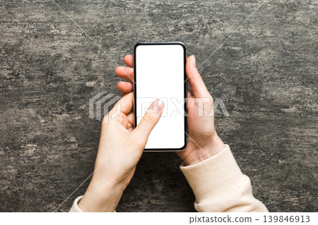 Top view of woman hands holding smart phone with blank copy space screen for your text message or information content. woman hand using phone white screen on top view Top view of woman hands holding smart phone with blank copy space screen for your text message or information content. woman hand using phone white screen on top view 139846913