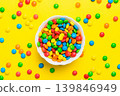 Multicolored candies in a bowl on a colored background. birthday and holiday concept. Top view with copy space 139846949