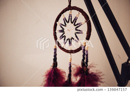 Handmade dream catcher with feathers hanging in a cozy room. Concept of modern mysticism, mindful home decor, and spiritual protection. Soft vintage aesthetic for interior design and wellness. 139847157