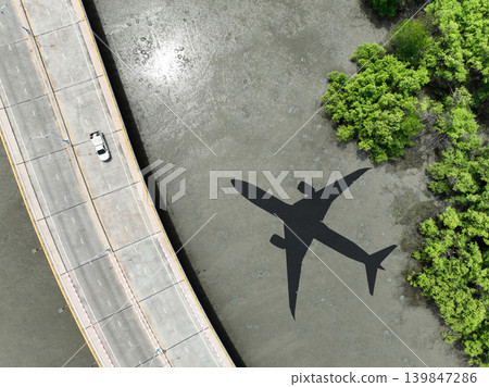 Airplane shadow flying over mangrove forest with car driving on coastal concrete bridge. Sustainable aviation biofuel technology. Environmental conservation. Eco-friendly flight. Mangroves capture CO2 Airplane shadow flying over mangrove forest with car driving on coastal concrete bridge. Sustainable aviation biofuel technology. Environmental conservation. Eco-friendly flight. Mangroves capture CO2 139847286
