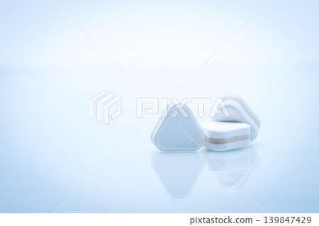 Triangle shape layered tablet pills for antacid digestive and gastric pain relief on white background in pharmaceutical concept. Multilayer formulation for effective treatment and healthcare use. Triangle shape layered tablet pills for antacid digestive and gastric pain relief on white background in pharmaceutical concept. Multilayer formulation for effective treatment and healthcare use. 139847429