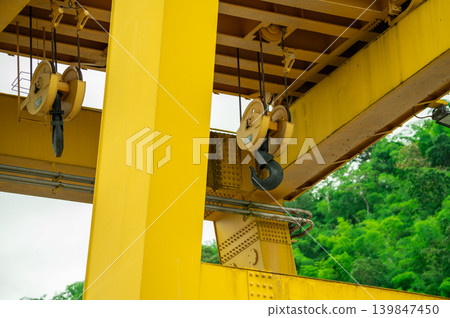 30-ton crane hook installed on hydroelectric dam. Lifting electric equipment, repairing turbines, and managing water flow. Maintenance operations. Construction, engineering, and industrial safety. 30-ton crane hook installed on hydroelectric dam. Lifting electric equipment, repairing turbines, and managing water flow. Maintenance operations. Construction, engineering, and industrial safety. 139847450