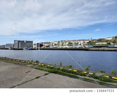 Peaceful River Scene with Plants and Buildings Under a Cloudy Sky 139847555