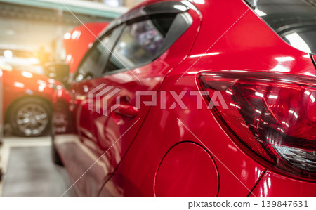 Rear view of red SUV car parked in car repair shop. Red car in workshop of service station. Vehicle inside garage workshop. Cleseup tailight. Red car in garage for repair and maintenance service. Rear view of red SUV car parked in car repair shop. Red car in workshop of service station. Vehicle inside garage workshop. Cleseup tailight. Red car in garage for repair and maintenance service. 139847631