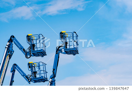 Articulated boom lift. Aerial platform lift. Telescopic boom lift against blue sky. Mobile construction crane for rent and sale. Maintenance and repair hydraulic boom lift service. Crane dealership. Articulated boom lift. Aerial platform lift. Telescopic boom lift against blue sky. Mobile construction crane for rent and sale. Maintenance and repair hydraulic boom lift service. Crane dealership. 139847647