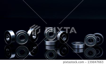 Stainless steel ball bearing on blackk background. Set of thrust ball bearing and silver ball bearing. Spare parts for roller machine in heavy machinery and automotive industry. Round metal wheel. 139847663