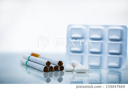 Nicotine chewing gum in blister pack near pile of cigarette. Quit smoking by use nicotine gum for relief of nicotine withdrawal symptoms. Medicine for giving up smoking. World no tobacco day concept. 139847669