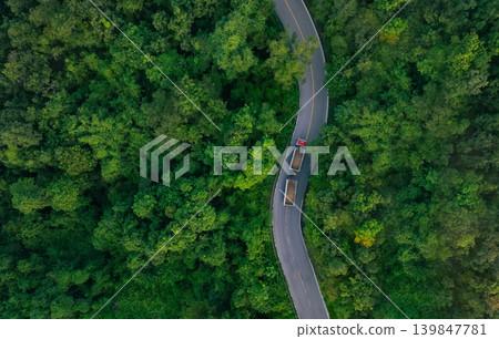 Aerial view of hydrogen energy truck driving on highway road in green forest. Sustainable transportation. Blue truck driving on asphalt road in forest. Hydrogen fuel cell vehicle. Zero emission car. Aerial view of hydrogen energy truck driving on highway road in green forest. Sustainable transportation. Blue truck driving on asphalt road in forest. Hydrogen fuel cell vehicle. Zero emission car. 139847781