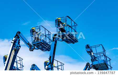 Articulated boom lift. Aerial platform lift. Telescopic boom lift against blue sky. Mobile construction crane for rent and sale. Maintenance and repair hydraulic boom lift service. Crane dealership. Articulated boom lift. Aerial platform lift. Telescopic boom lift against blue sky. Mobile construction crane for rent and sale. Maintenance and repair hydraulic boom lift service. Crane dealership. 139847787