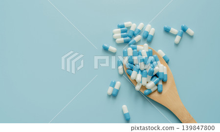 Blue-white antibiotic capsule pills on wooden spoon and blue background. Antibiotic drug resistance. Prescription drug. Medical care. Pharmaceutical care. Antimicrobial drug. World Pharmacist Day. Blue-white antibiotic capsule pills on wooden spoon and blue background. Antibiotic drug resistance. Prescription drug. Medical care. Pharmaceutical care. Antimicrobial drug. World Pharmacist Day. 139847800