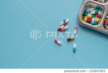 Above view of Colorful antibiotic capsule pills on a tray and blue background. Antibiotic drug resistance. Antimicrobial drugs. Prescription drugs. Pharmaceutical industry. Health care and medicine. Above view of Colorful antibiotic capsule pills on a tray and blue background. Antibiotic drug resistance. Antimicrobial drugs. Prescription drugs. Pharmaceutical industry. Health care and medicine. 139847801