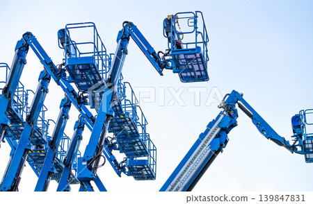 Articulated boom lift. Aerial platform lift. Telescopic boom lift against clear sky. Mobile construction crane for rent and sale. Maintenance and repair hydraulic boom lift service. Crane dealership. Articulated boom lift. Aerial platform lift. Telescopic boom lift against clear sky. Mobile construction crane for rent and sale. Maintenance and repair hydraulic boom lift service. Crane dealership. 139847831