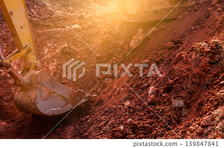 Metal bucket of backhoe digging soil. Backhoe working by digging soil at the construction site. Excavator digging on dirt soil. Earth moving machine. Excavation vehicle. Construction business. 139847841