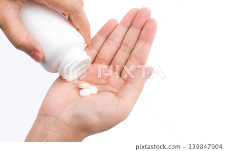 Woman hand pouring tablet pills from white plastic bottle into palm isolated on white background. Healthcare concept. Medication use, dosage control and daily treatment routine for adult patient care. Woman hand pouring tablet pills from white plastic bottle into palm isolated on white background. Healthcare concept. Medication use, dosage control and daily treatment routine for adult patient care. 139847904