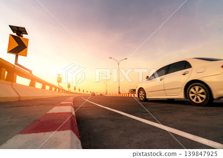 Car driving on curved concrete road with motion blur. Road trip travel. Traffic warning sign, modern transportation and eco awareness on scenic route. Summer vacation journey and automotive travel. 139847925