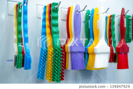 Brushes hang on shelf. Color coded hygiene glazing brushes and detail brushes for food processing and manufacturing. Cleaning tool for food safety in food and beverage industry. Durable cleaning brush Brushes hang on shelf. Color coded hygiene glazing brushes and detail brushes for food processing and manufacturing. Cleaning tool for food safety in food and beverage industry. Durable cleaning brush 139847929