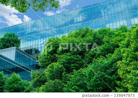 Eco-friendly building in modern city. Sustainable glass office building with trees for reducing CO2. Green architecture. Building with green environment. Sustainability corporate. Net zero emissions. Eco-friendly building in modern city. Sustainable glass office building with trees for reducing CO2. Green architecture. Building with green environment. Sustainability corporate. Net zero emissions. 139847973