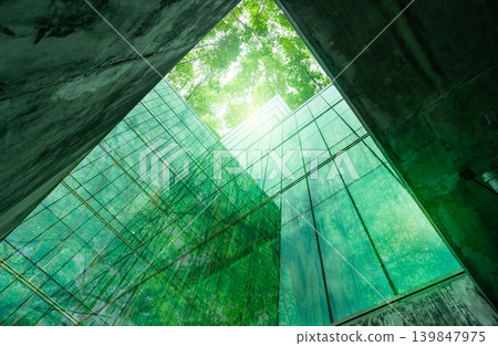 Eco-friendly building in the modern city. Sustainable glass office building with tree for reducing heat and carbon dioxide. Office building with green environment. Corporate building reduce CO2. Eco-friendly building in the modern city. Sustainable glass office building with tree for reducing heat and carbon dioxide. Office building with green environment. Corporate building reduce CO2. 139847975