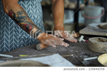 An adult man makes a ceramic plate in a workshop An adult man makes a ceramic plate in a workshop 139848358