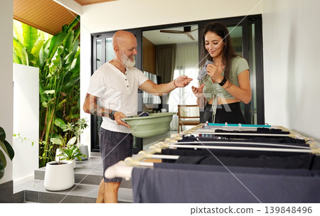 Man and woman collaborate to fold laundry outdoors on modern terrace 139848496