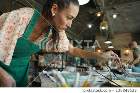 A young woman makes a ceramic plate in a workshop A young woman makes a ceramic plate in a workshop 139848522