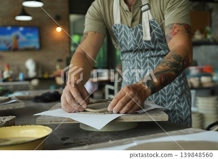 An adult man makes a ceramic plate in a workshop An adult man makes a ceramic plate in a workshop 139848560