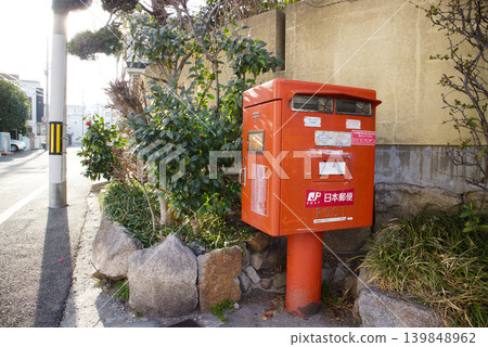 特寫：一個紅色郵筒被石牆和綠植環繞。 139848962
