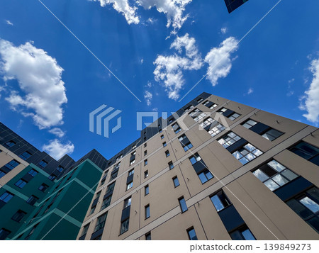 View of a modern house facade with many windows and a blue sky overhead. Clouds are scattered, giving a bright look in the daytime View of a modern house facade with many windows and a blue sky overhead. Clouds are scattered, giving a bright look in the daytime 139849273