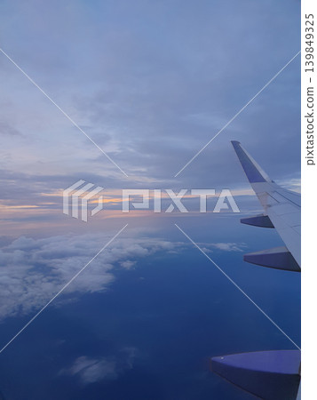 Phone photo of the Earth at twilight, viewed from an airplane. Dramatic aerial scene showing the horizon, fading sunlight, and atmospheric layers from high altitude. Phone photo of the Earth at twilight, viewed from an airplane. Dramatic aerial scene showing the horizon, fading sunlight, and atmospheric layers from high altitude. 139849325