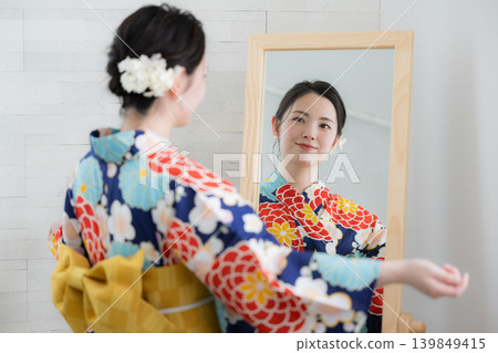 Image of a Japanese woman checking her yukata in the mirror as she prepares to get dressed. Image of a Japanese woman checking her yukata in the mirror as she prepares to get dressed. 139849415