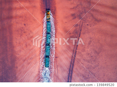 Aerial top down view of an old train rides on the railway laid in the water through the salt lake. Salt mining in Lake Burlin. Altai. Bursol. Aerial top down view of an old train rides on the railway laid in the water through the salt lake. Salt mining in Lake Burlin. Altai. Bursol. 139849520