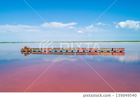 Aerial top down view of an old train rides on the railway laid in the water through the salt lake. Salt mining in Lake Burlin. Altai. Bursol. 139849540