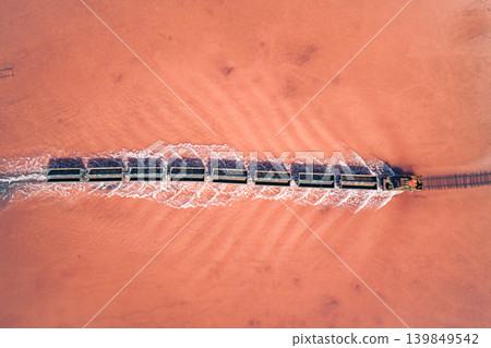Aerial top down view of an old train rides on the railway laid in the water through the salt lake. Salt mining in Lake Burlin. Altai. Bursol. Aerial top down view of an old train rides on the railway laid in the water through the salt lake. Salt mining in Lake Burlin. Altai. Bursol. 139849542