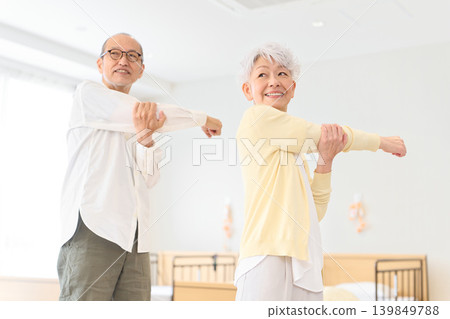 Senior men and women doing stretches at a nursing home. Senior men and women doing stretches at a nursing home. 139849788