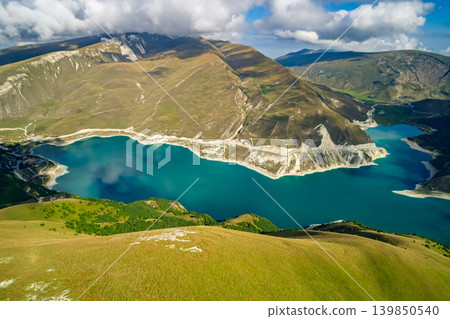 Panoramic view capturing Lake Kazenoy's striking turquoise waters contrasting with steep, sun-kissed mountains Panoramic view capturing Lake Kazenoy's striking turquoise waters contrasting with steep, sun-kissed mountains 139850540