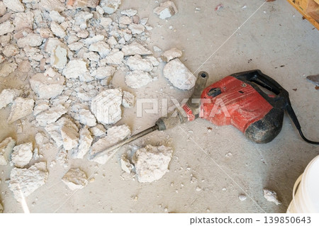 Electric demolition hammer on floor with broken concrete debris Electric demolition hammer on floor with broken concrete debris 139850643