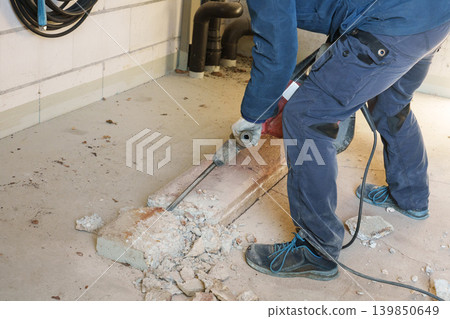 Worker using jackhammer to break concrete floor during renovation Worker using jackhammer to break concrete floor during renovation 139850649